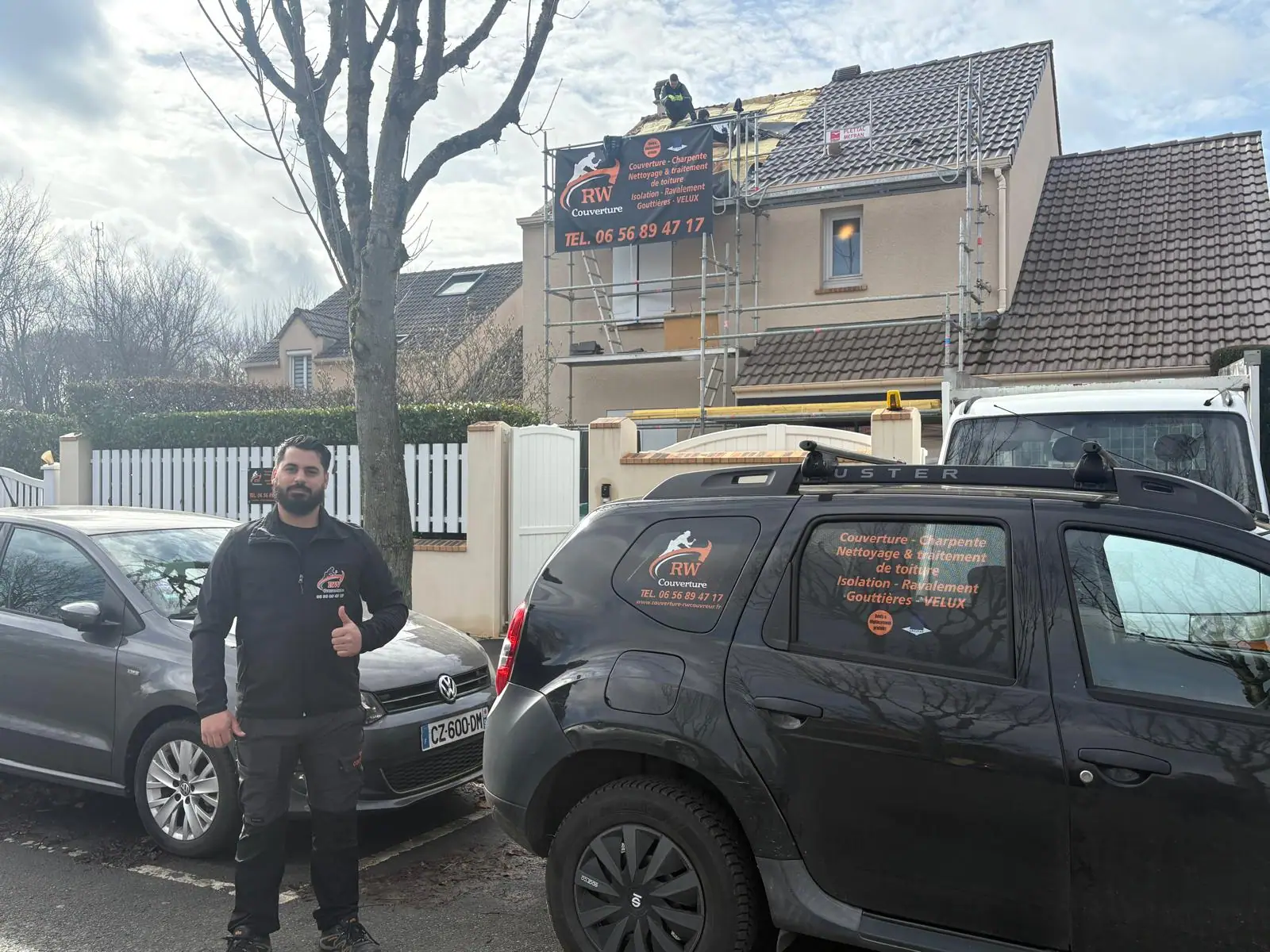 Véhicule d'intervention floqué aux couleurs de RW Couvreur, devant un chantier de toiture monté sous échafaudage