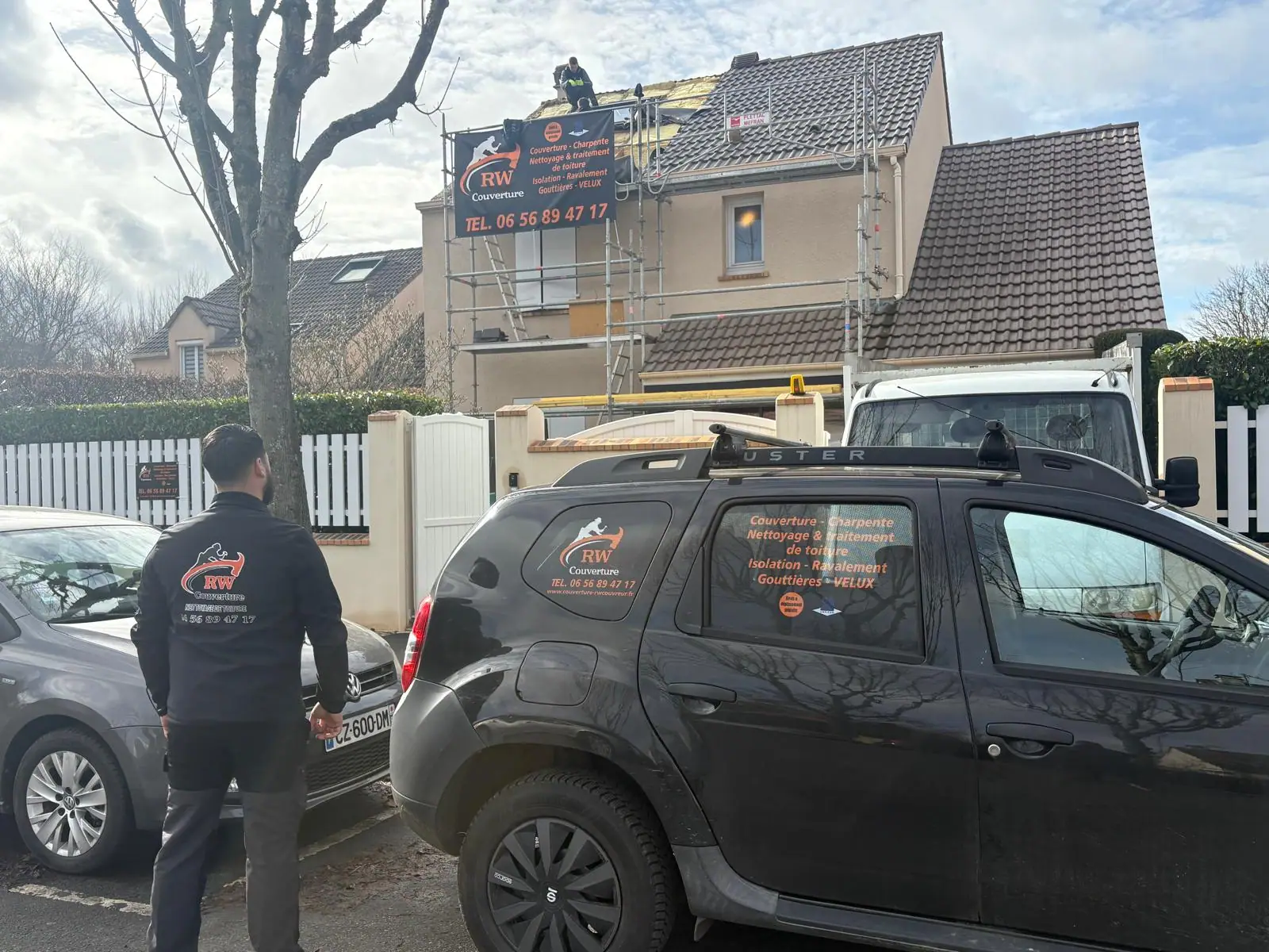 Versant ouvert et liteaux nus, deux couvreurs en haut d'un échafaudage bâché aux couleurs de l'entreprise — RW Couvreur