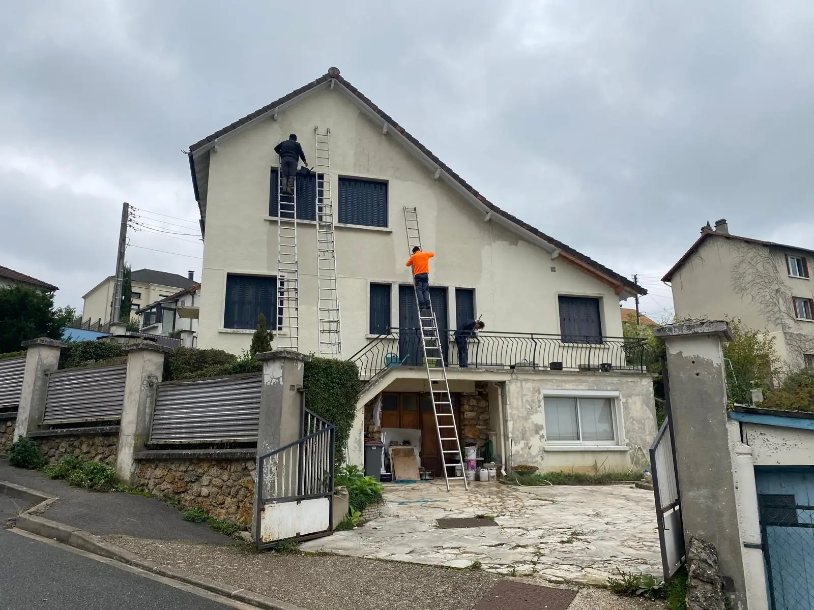 Trois ouvriers sur échelles en train de traiter la façade d’une maison — RW Couvreur