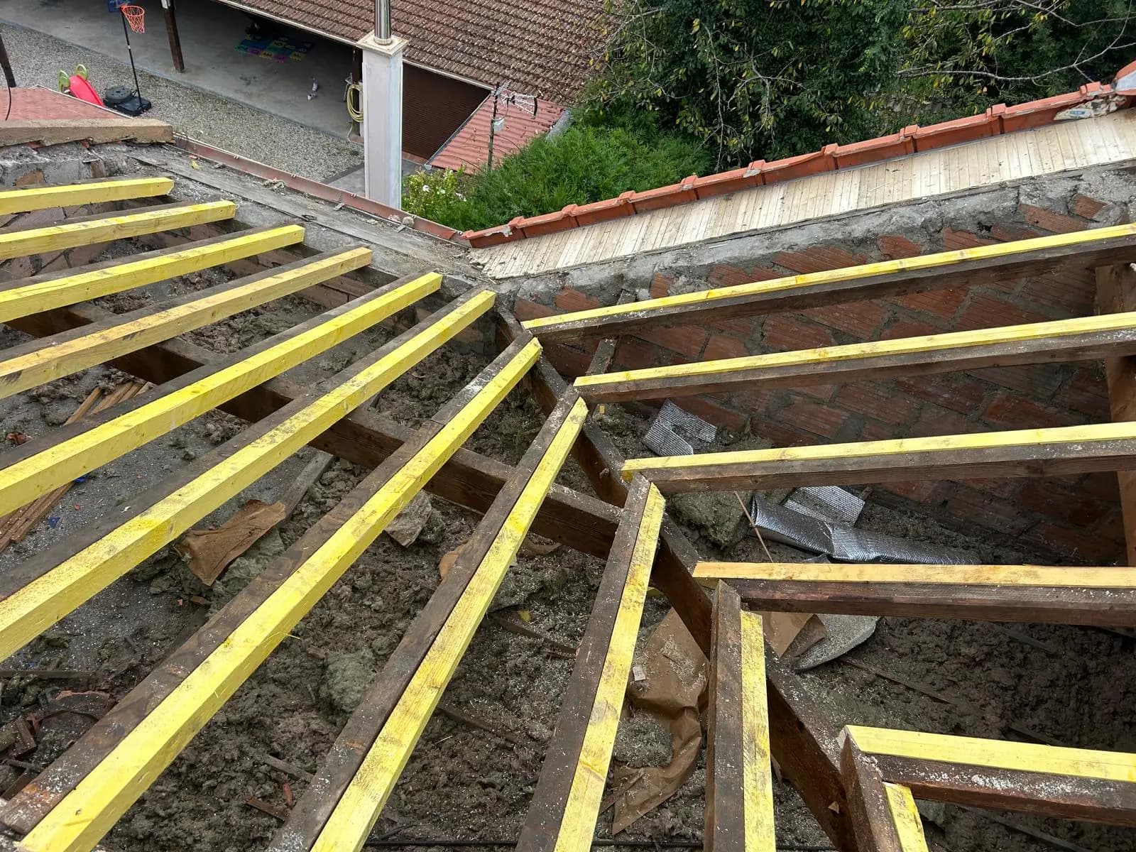 Chevrons neufs traités posés sur la maçonnerie à côté de l’ancienne charpente déposée — RW Couvreur