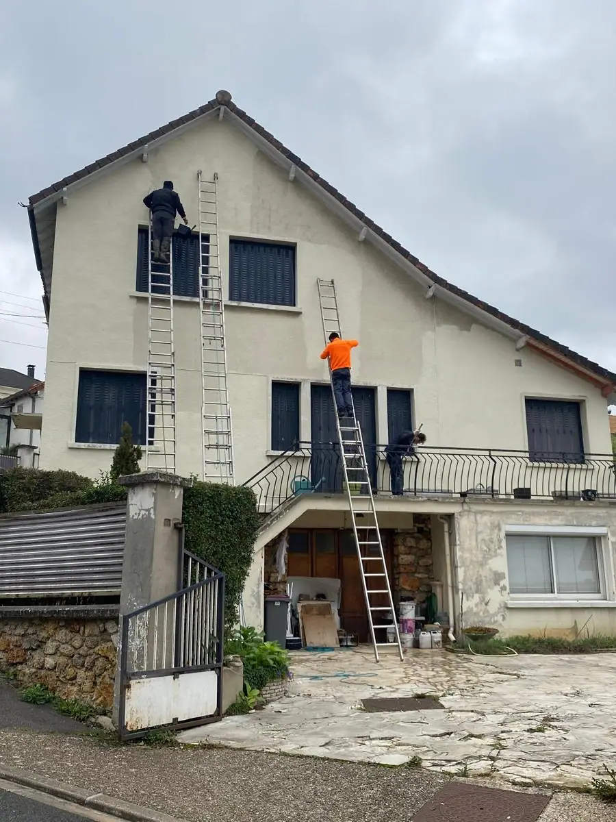 Ravalement de façade en cours, deux échelles dressées contre le pignon